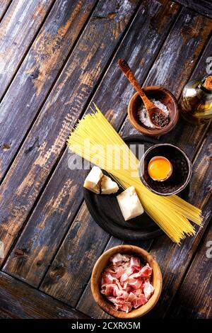 Zutaten für traditionelle italienische Pasta alla Carbonara. Ungekochte Spaghetti, bauchspeck Speck, Parmesan, Eigelb, Salz, Pfeffer in Olivenholz bo Stockfoto