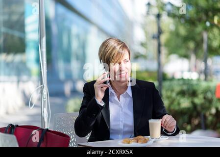 Porträt einer Geschäftsfrau im Gespräch auf Handy bei Café-Bar Stockfoto