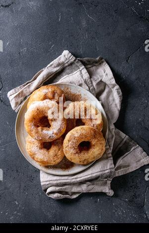 Teller mit hausgemachten Krapfen mit Zucker und Zimt Pulver auf Grau textile Serviette über dunkle Textur Hintergrund. Ansicht von oben mit der Kopie Raum Stockfoto