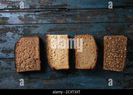 Verschiedene Brote in Scheiben hausgemachtes Roggenbrot Vollkorn und Samen über Altes, dunkles Holz- Hintergrund. Ansicht von oben, Platz. Gesunde Ernährung Stockfoto