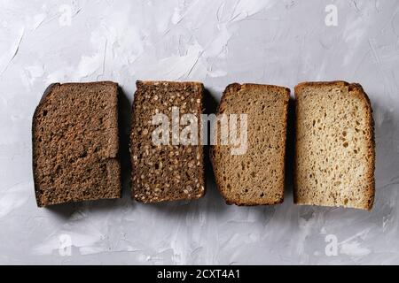 Verschiedene Brote in Scheiben hausgemachtes Roggenbrot Vollkorn und Samen über grau Textur Hintergrund. Ansicht von oben, kopieren. Gesunde Ernährung Stockfoto