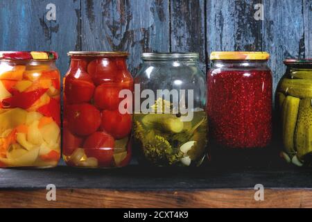 Vielzahl Glas Gläser hausgemachte eingelegte oder fermentierten Gemüse und Staus in der Zeile mit alten, dunklen Blau Holzbrett Hintergrund. Saisonale bewahrt. Stockfoto
