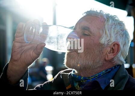 Älterer Mann, der den letzten Tropfen OPF Bier aus einem Glas entwässert, England Stockfoto