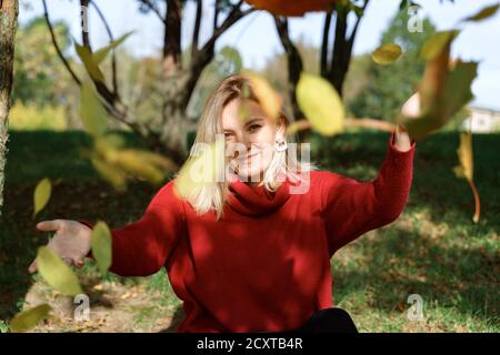 Schöne junge blonde Frau wirft Herbst Wahrheiten. Herbst-Konzept Stockfoto