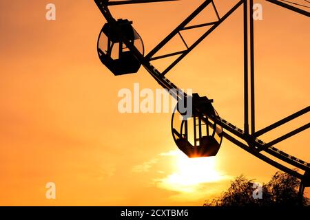 Riesenrad auf dem Jahrmarkt während des malerischen Sonnenuntergangs Stockfoto