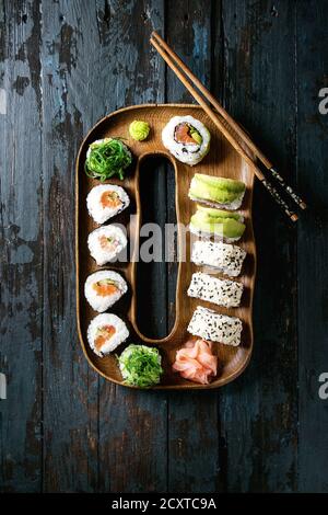 Hausgemachte sushi Brötchen mit Lachs, Sesam und Avocado in Holz Platte serviert mit Rosa eingelegter Ingwer, Sojasauce, Wasabi, Algensalat, Koteletts Stockfoto