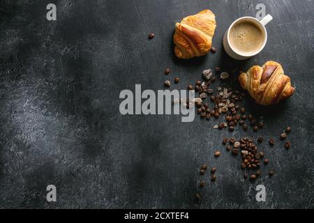 Frisch gebackene Croissants und traditionelle Tasse Espresso Kaffee, Kaffeebohnen, Zucker über schwarzen Textur Hintergrund. Ansicht von oben, kopieren Raum Stockfoto