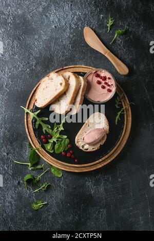 Huhn hausgemachter Leberpastete oder Pastete mit in Scheiben Vollkornbrot, Messer, Preiselbeeren, grüner Salat im Glas Glas auf Holz- Schiefer serviert, das Board Stockfoto