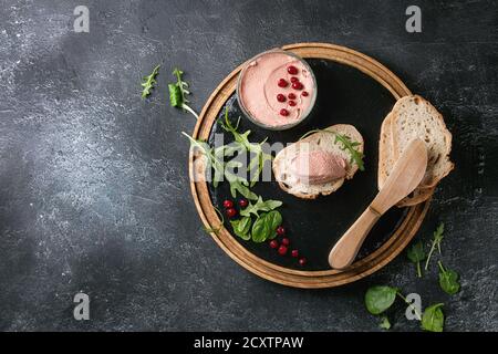 Huhn hausgemachter Leberpastete oder Pastete mit in Scheiben Vollkornbrot, Messer, Preiselbeeren, grüner Salat im Glas Glas auf Holz- Schiefer serviert, das Board Stockfoto