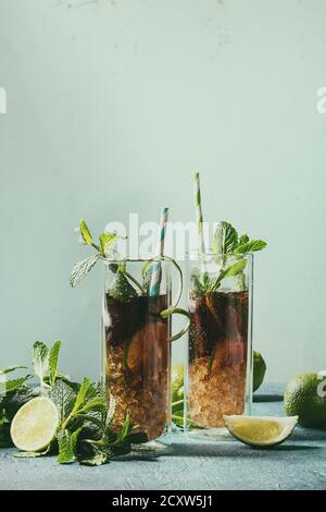 Zwei Gläser classic Cuba Libre Cocktail mit Limetten, Minze, crushed Eis und Cola, Zutaten, cocktail Rohre über türkis grün Pin-up-Stil Stockfoto