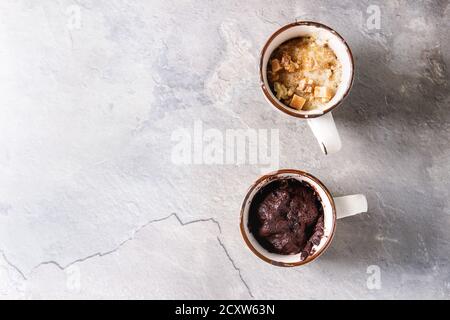 Schokolade und Vanille Karamell Becher Kuchen aus der Mikrowelle über grau Textur Hintergrund. Ansicht von oben, kopieren Raum Stockfoto