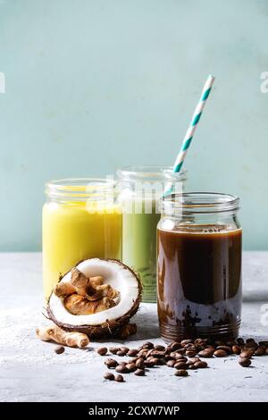 Vielzahl von bunten Iced Latte Getränke. Eiskaffee, Kurkuma und Matcha Latte Cocktails in Gläsern mit Zutaten oben über Grau Grün Textur b Stockfoto