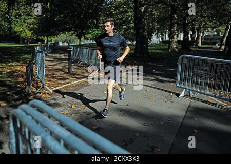 Ein Läufer auf der Strecke des 40. London Marathon, der auf einer Rundstrecke rund um den St James's Park im Zentrum von London stattfinden wird. Die Athleten der Elite-Rennen menís, womenís und des Rollstuhls werden auf einer geschlossenen Looped-Strecke im St. JamesÍs Park in einer biosicheren Blase antreten. Stockfoto