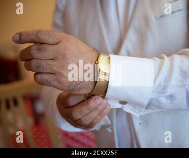 Der Mensch legt eine goldene Uhr auf seine Hand. Stockfoto