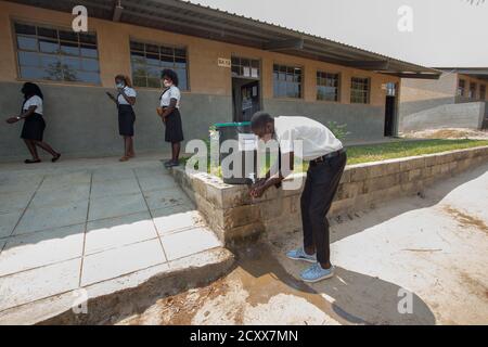 Die Schüler kehren nach der Pause wieder in die Schule zurück, mit der neuen Normalität der sozialen Distanz, mit Masken und Händewaschen vor dem Unterricht Stockfoto