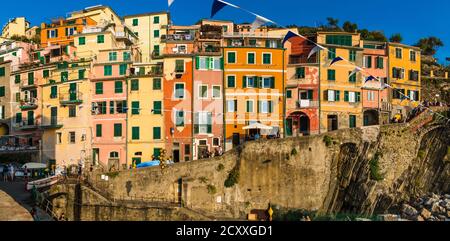 Schöne große Nahaufnahme Panorama der historischen bunten Turmhäuser in einer Reihe am Kai im beliebten Zentrum von Riomaggiore an einem schönen sonnigen Abend... Stockfoto