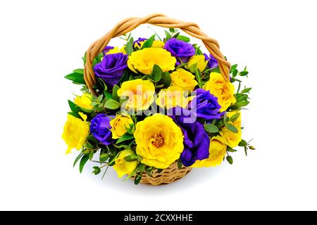 Korb mit gelben und blauen Blüten auf isoliertem weißem Hintergrund. Bouquet von gelben und lila Rosen. Schöne Blumen in einem Weidenkorb. Bouquet von Stockfoto