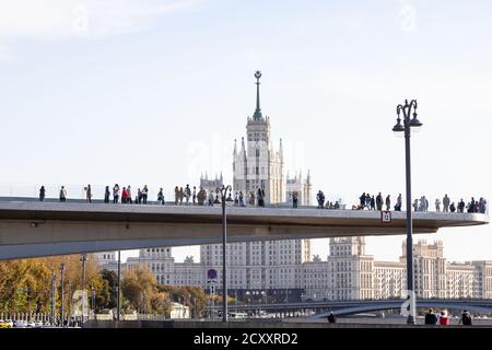 MOSKAU, RUSSLAND - 27. SEPTEMBER 2020: Die schwimmende Brücke mit Touristen in der Nähe von Zaryadye Landschaftspark und Kotelnicheskaya Embankment Hochhaus Stockfoto