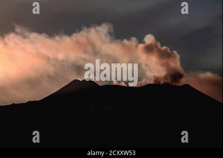 Strahlen aus der untergehenden Sonne hinterleuchtete Rauchwolken und schwebende Schwefelgaswolken aus Gipfelkrater auf dem Ätna, Sizilien, Italien, in dieser Ansicht aus dem Osten im August 2011. Der Ätna ist der höchste aktive Vulkan Westeuropas. Die Aktivität begann vor 500,000 Jahren mit vielen hochexplosiven Eruptionen seitdem. Seit 1600 gab es 60 Eruptionen durch Seitenschlitze und viele weitere vom Gipfel, einschließlich jener in den Jahren 2006, 2007-8, 2012 und 2018. Ätna war ziemlich ruhig im Jahr 2011, aber intensive Aktivität ab Januar 2012 zwang die vorübergehende Schließung des Catania International Airport. Stockfoto