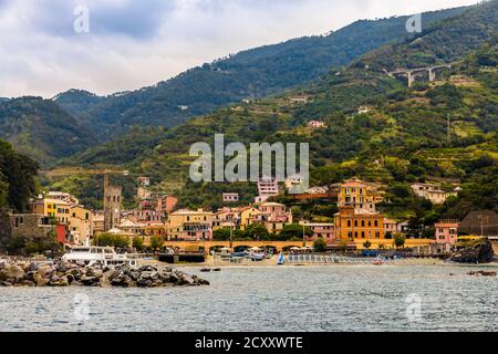 Tolle Nahaufnahme des Strandes mit dem Hafen, dem mittelalterlichen Glockenturm und den bunten Gebäuden mit den Hügeln im Hintergrund im alten Teil... Stockfoto