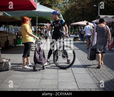 Belgrad, Serbien, 17. Sep 2020: Straßenszene mit einer Frau, die sich mit dem Radfahrer auf dem Bauernmarkt unterhielt Stockfoto