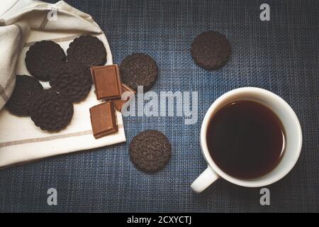 Braune Kekse und Schokolade liegen neben Kaffee in einem becher Stockfoto