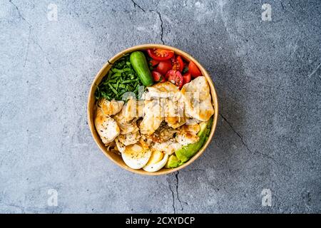 Gesunde Protein Fitness Food Hähnchen, Ei, Spinat, Avocado und Gurke mit Fitnessgeräten Hanteln für Sportler in Plastikschüssel. Bereit zum Essen. Stockfoto