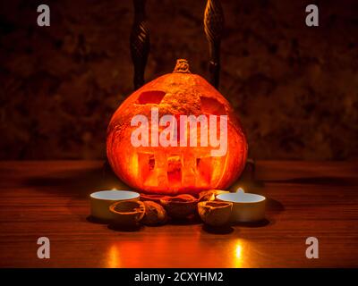 Halloween Thema - geschnitzte Kürbis und Walnussschalen im Dunkeln, beleuchtet von zwei Kerzen Stockfoto