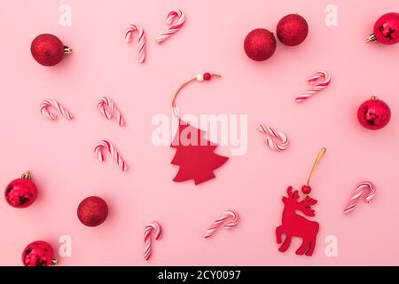 Neujahrsgestaltung. Rote Spielzeuge, Zuckerstöcke und Konfetti auf rosa. Flach liegend, Draufsicht. Stockfoto
