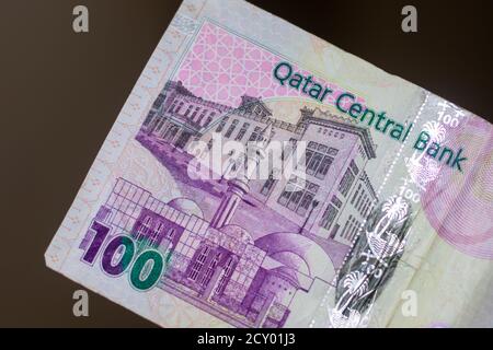 Währung des Katar - Purple hundert rial oder riyal Noten auf einem braunen Hintergrund verteilt. Geldwechsel. Stockfoto