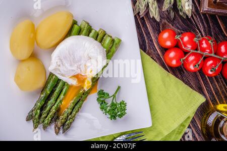 Grüner Spargel und gekochtes pochiertes Ei auf einem weißen Teller. Stockfoto