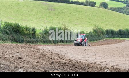 Roter tschechischer Zetor Traktor / Forterra 140 HSX Bodenbearbeitungsfeld mit spiralförmiger Krümelwalze hinter Traktor. Unsicher, ob auch Zinken kultiviert werden. Stockfoto