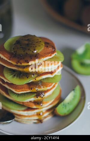 Teller mit Pfannkuchen tropfend mit Kiwi Marmelade mit Kiwi Stücke. Fastnacht Maslenitsa Butter Woche Festival Mahlzeit. Faschingsdienstag. Pfannkuchentag Stockfoto