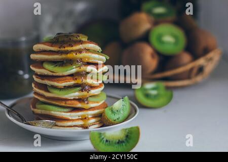 Teller mit Pfannkuchen tropfend mit Kiwi Marmelade mit Kiwi Stücke. Fastnacht Maslenitsa Butter Woche Festival Mahlzeit. Faschingsdienstag. Pfannkuchentag Stockfoto