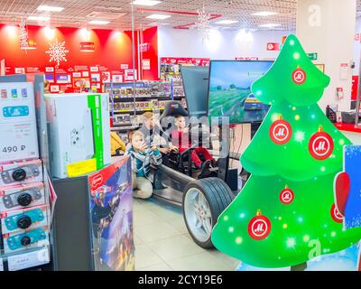 Sotschi, Russland - 14. Dezember 2019. Kinder, die ein Auto fahren und ein Videospiel in einem Elektronikgeschäft spielen Stockfoto