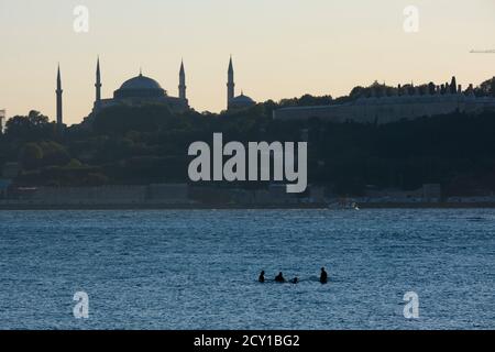 Istanbul, Türkei - 1. September 2020: Vier Männer stehen mitten im Istanbuler Bosporus auf und das sieht seltsam aus. Die Hagia Sophia Stockfoto