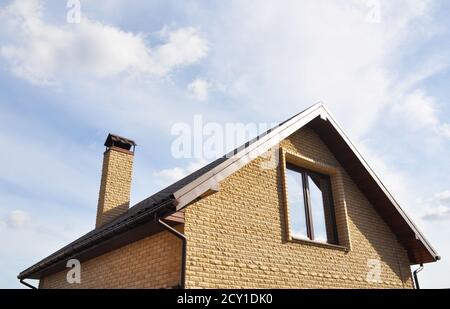 Dachgeschosskonstruktion im Freien. Dachkonstruktion mit Ziegelkamin und Dachrinnen-System. Mansardendach. Stockfoto