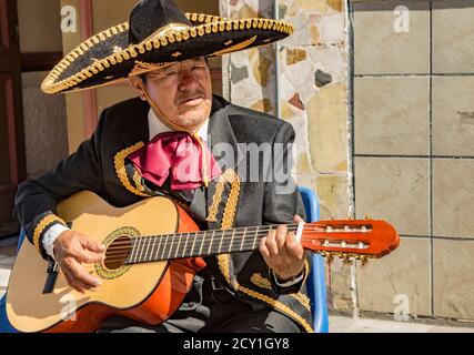 Cuenca, Ecuador Dec 24, 2017 - der Mann spielt akustische Gitarre, während er in einem traditionellen Mariachi-Anzug gekleidet ist Stockfoto