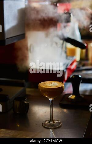 Café Latte oder Kaffee Piccolo mit herzförmiger Latte-Kunst in einem martini-Glas oder Cocktailglas. Flacher freiheitsgrad Stockfoto