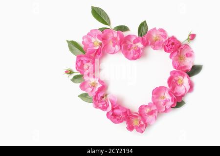 Herz aus Köpfen und Knospen aus Rosen und Blättern auf weißem Hintergrund. Draufsicht und Kopierbereich. Valentinstag-Konzept. Stockfoto