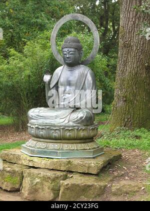 Eine Bronzestatue von Buddha wurde 1900 von der Familie Mitford für das Gelände des Batsford Arboretum importiert. Stockfoto