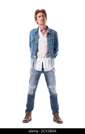 Stilvolle junge männliche Mode-Modell mit roten Haaren in Jeans wegschauen mit Händen auf dem Rücken. Ganzkörper isoliert auf weißem Hintergrund. Stockfoto