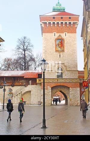 KRAKAU, POLEN - 30. DEZEMBER 2010: Touristen und Einheimische verbringen ihre Zeit in der Nähe von St. Florians Tor am Morgen im Winter Stockfoto