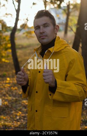 Selbstbewusster Mann im gelben Regenmantel im Herbst Park, Stockfoto