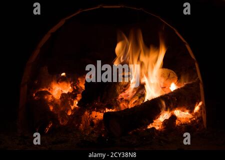 Russischer Herd. Rot orange gelb brennendes Holz. Traditioneller Ofen mit Flamme, Brennholz und Kohlen. Stockfoto