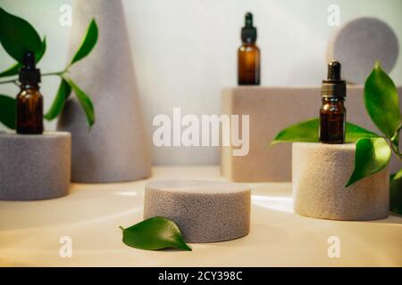 Trendiger Hintergrund geometrischer Formen mit natürlichen ätherischen Ölen Flaschen, frischen Blättern und leerem zentralen Podium zur Produktpräsentation. Schönheit und Stockfoto