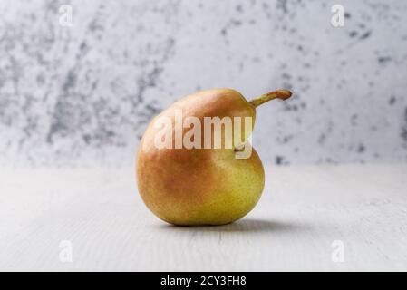 Trendige hässliche Bio-Früchte -eine grüne Birne auf dem Tisch mit Platz für Text kopieren. Stockfoto