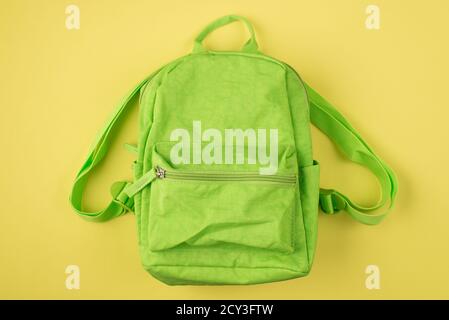 Zurück zur Schule Konzept. Oben über der Ansicht von oben Foto des grünen Rucksacks isoliert auf gelbem Hintergrund Stockfoto