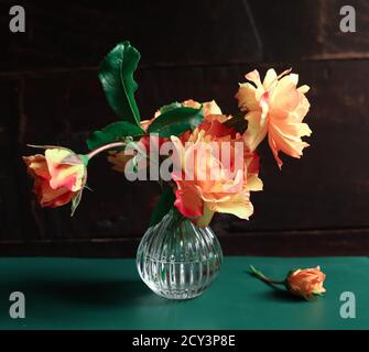 Bouquet von schönen orangefarbenen Rosen auf einem grünen Tisch Ein dunkler Hintergrund Stockfoto