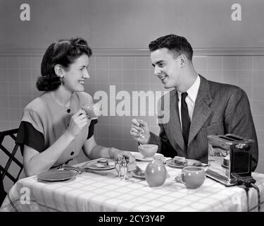 1940ER JAHRE JUNG VERHEIRATET PAAR MANN FRAU SITZT AM FRÜHSTÜCKSTISCH REDEN TRINKEN KAFFEE BLICK AUF EINANDER ELEKTRISCHEN TOASTER - D2123 HAR001 HARS URBAN SHARING ALTE ZEIT BESCHÄFTIGT ZUKUNFT NOSTALGIE ALTE MODE 1 GERÄT STIL KOMMUNIKATION JUNGE ERWACHSENE BALANCE TOASTER TEAMWORK STARK ZUFRIEDEN FREUDE LIFESTYLE FRAUEN VERHEIRATET EHEPARTNER EHEMÄNNER MODERN HEALTHINESS HOME LEBEN KOPIEREN RAUM HALBE LÄNGE DAMEN PERSONEN PFLEGE MÄNNER B&W MORGENPARTNER ANZUG UND KRAWATTE GLÜCK WELLNESS FRÖHLICH AN AUF LÄCHELN VERBINDUNG KONZEPTIONELLE FREUDIG STILVOLLE PERSÖNLICHE BINDUNG ZUNEIGUNG EMOTION ZWEISAMKEIT FRAUEN JUNGEN ERWACHSENEN MANN Stockfoto
